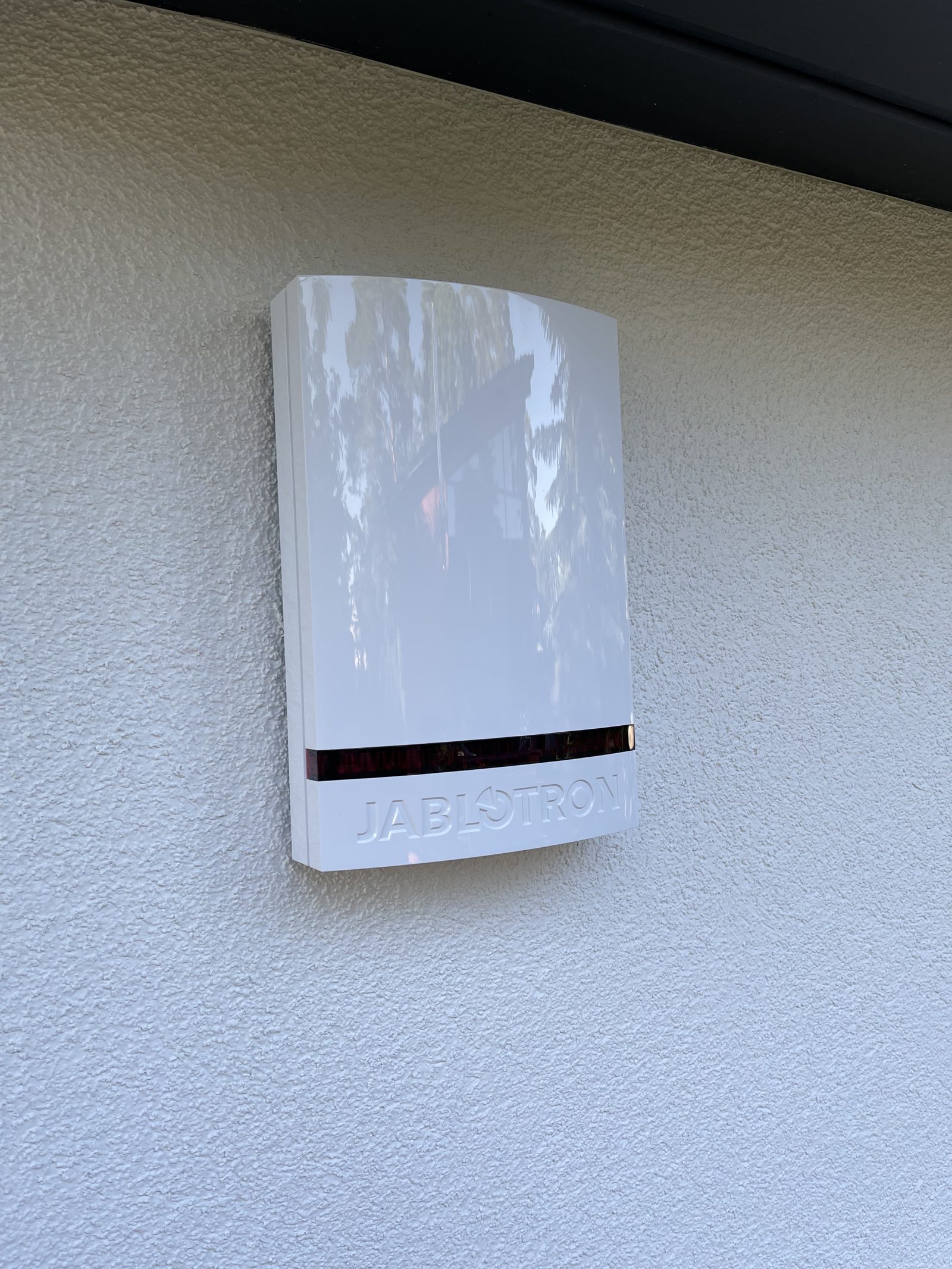 Weiße Außensirene einer Jablotron-Alarmanlage an einer Hausfassade, installiert von Hometec-Dietze